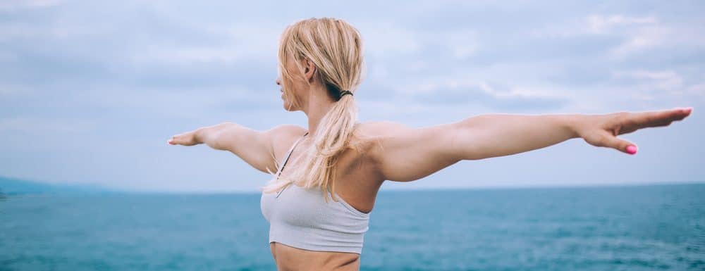 Young woman doing stretches by the oceanside